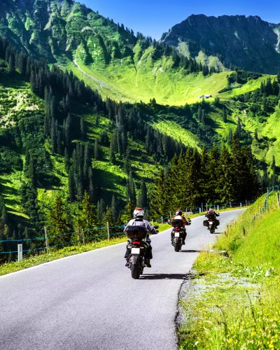 Group of travelling bikers in Alpine mountains, riding on mountainous highway, extreme lifestyle, spring travel and adventure concept